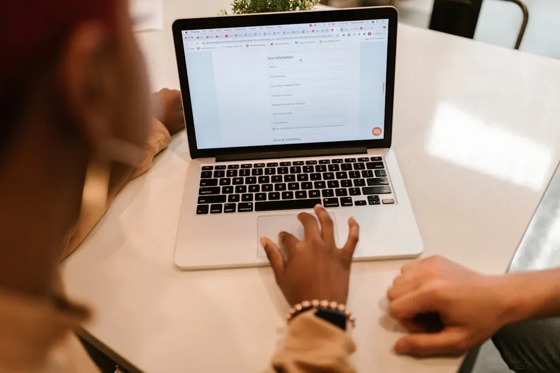 Two adults working together on a laptop displaying an online form, indoors