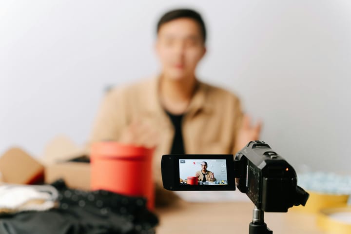 A blogger sits in front of a camera for filming a video indoors.